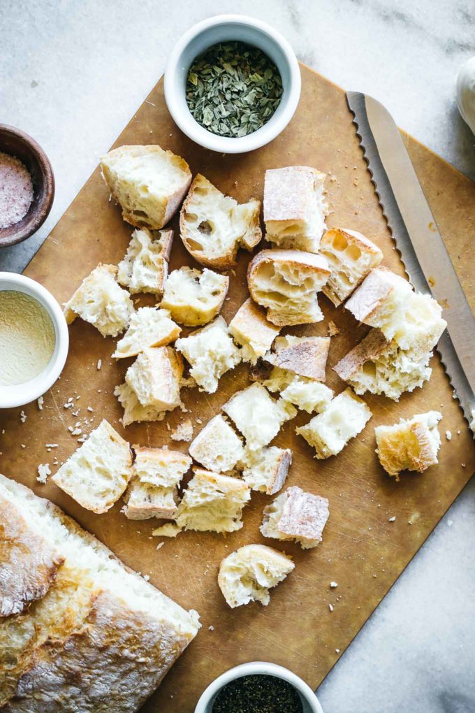 cut pieces of ciabatta bread on a wooden cutting board with a bread knife