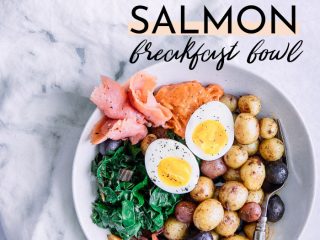 A savory breakfast bowl with soft-boiled egg, salmon, and potatoes on a white table with the words "smoked salmon breakfast bowl" in black writing.