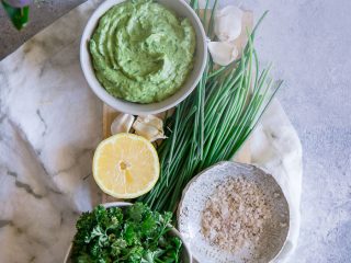 Parsley, chives, lemons, and salt made into a vegan dip on a blue table.