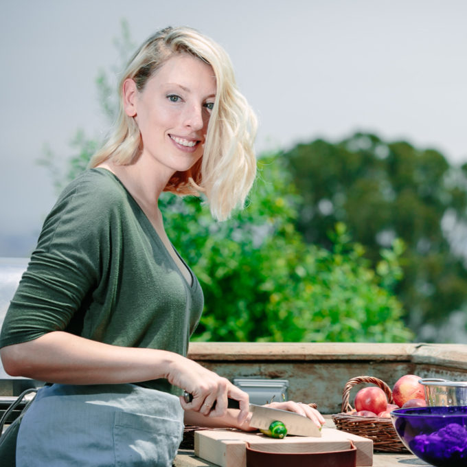 Kristina Todini, RDN of Fork in the Road cutting vegetables in an outdoor kitchen.