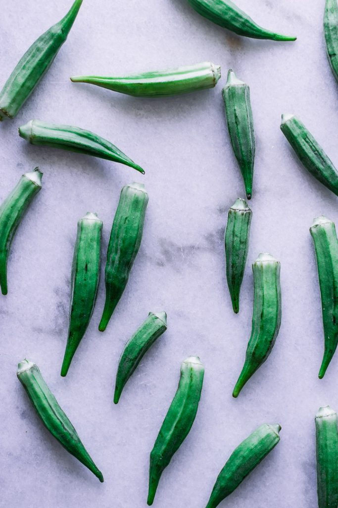 Assorted okra pods on white marble.