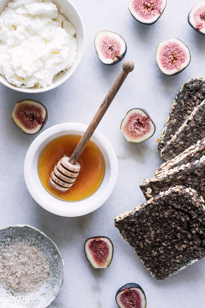 A pot of honey with assorted figs and wheat bread.