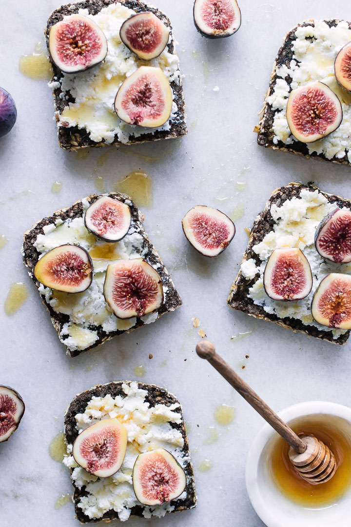 Five pieces of toast with ricotta cheese and honey on white marble.