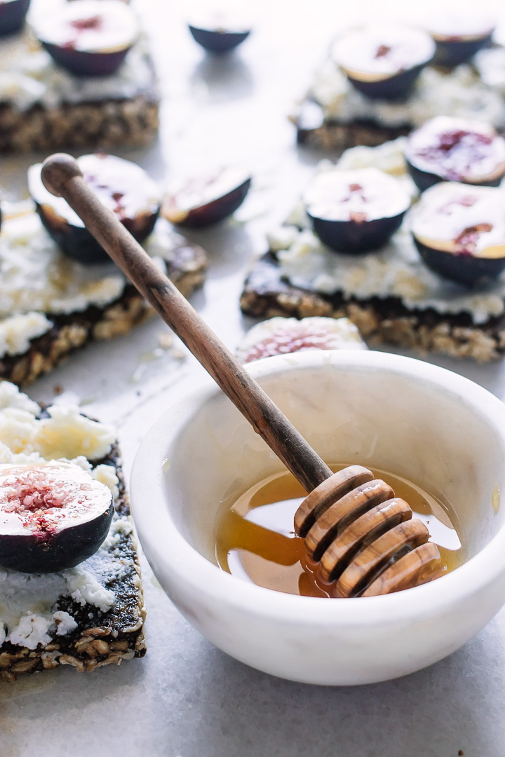 A small white bowl with honey and toast in the background.