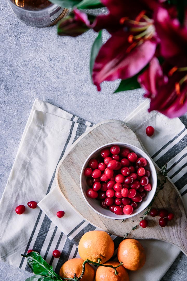 A bowl of cranberries on a table with flowers