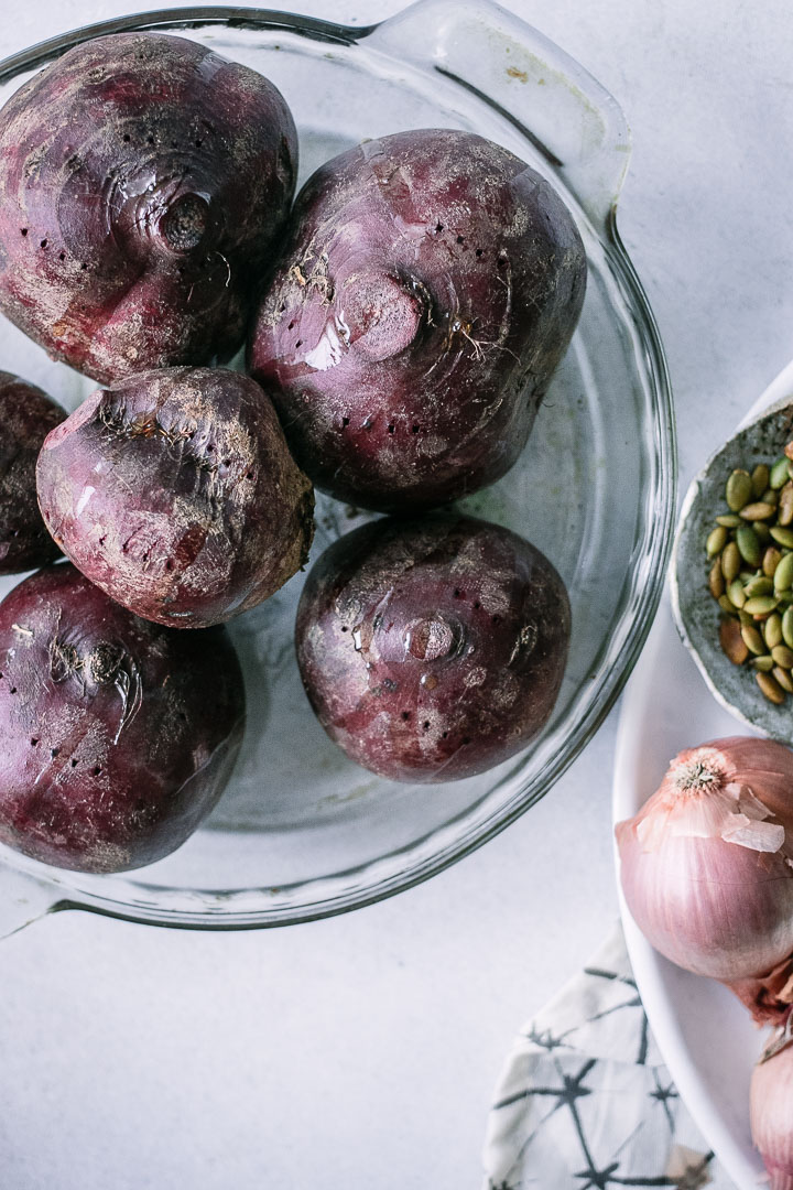 a glass baking dish with red beets on a white table