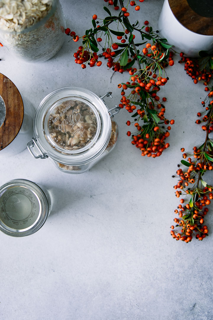 glass jars with nuts and seeds on a table with orange flowers