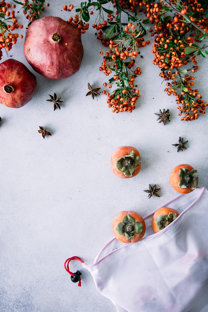 A reusable produce bag with persimmons on a white table