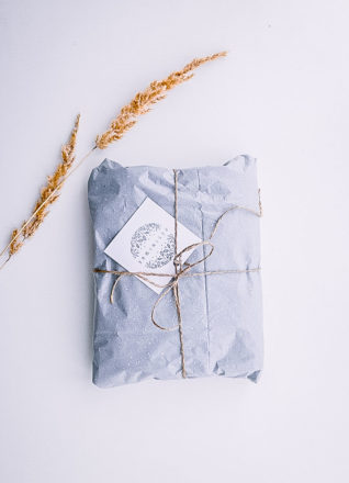 A blue gift-wrapped present with a twig of hay