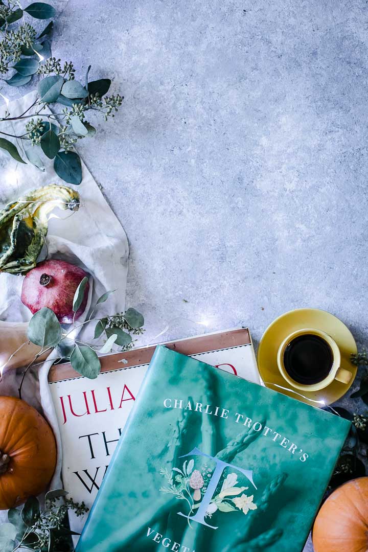 cookbooks and coffee on a blue table with winter vegetables and fruit