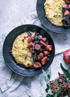 a black bowl with polenta and braised mushrooms and carrots