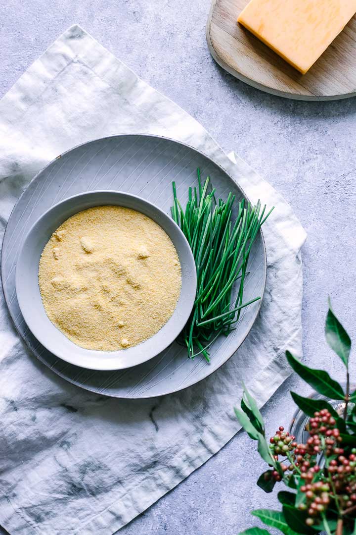 dry polenta in a bowl with herbs on a white table