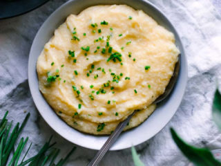 cheddar chive polenta in a blue bowl with a silver spoon