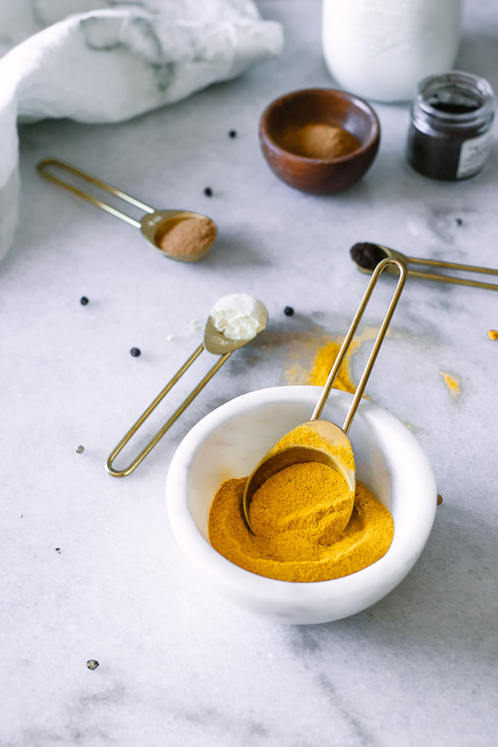 A small with bowl with yellow turmeric and measuring cups