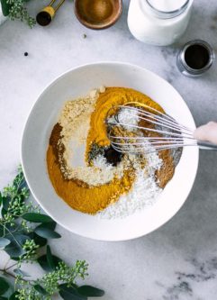 a hand mixing golden milk spices in a bowl with a whisk