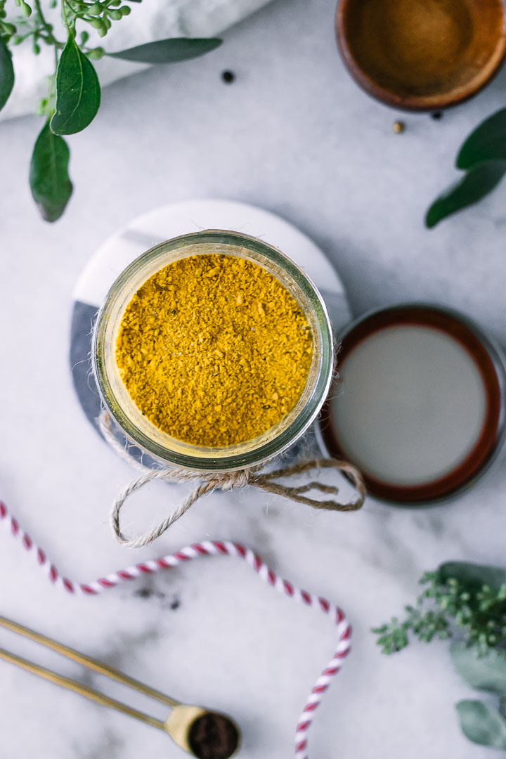 A bowl of yellow turmeric on a piece of marble with a red bow