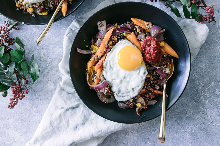 two black bowls with a quinoa grain salad and a sunny egg on top