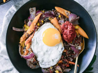 A black bean and quinoa salad in a black bowl on a white table