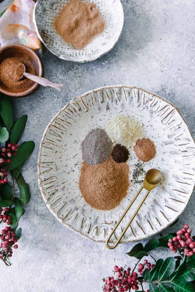 cinnamon, cardamom, ginger, nutmeg, cloves, and pepper in a white bowl