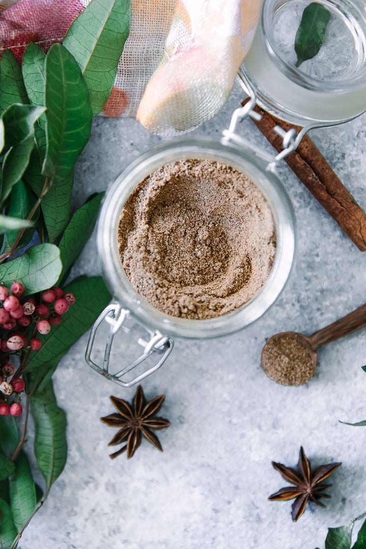 a glass jar with chai spices and a small wooden spoon