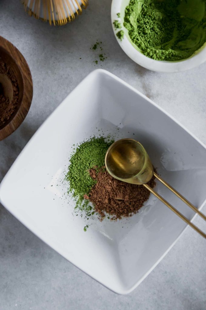 a bowl with matcha powder and cocoa powder and a gold spoon