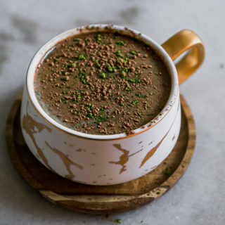 a mocha latte with green matcha powder in a white mug on a white table