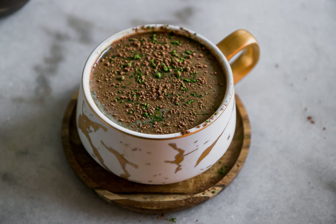a mocha latte with green matcha powder in a white mug on a white table