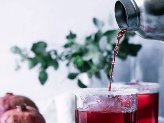 margarita pouring into glass with words "pomegranate margarita" in black and red writing