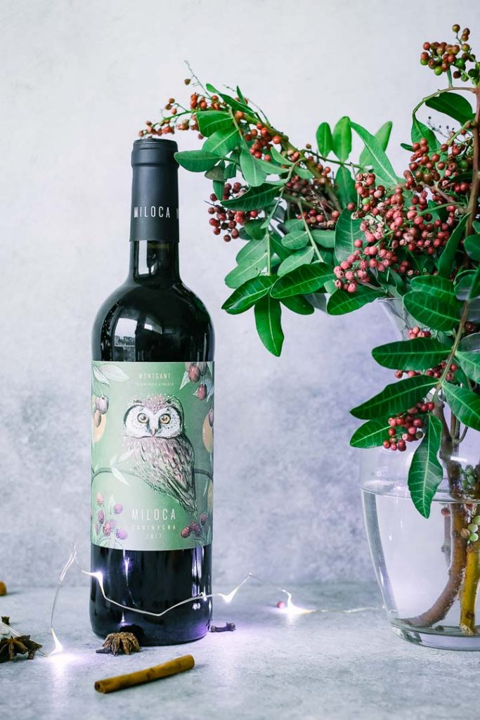 a bottle of red wine on a table with christmas flowers