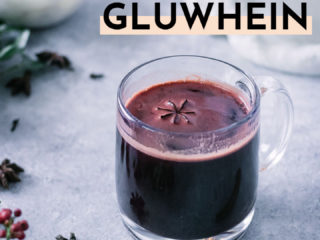 a mug of red wine on a white table with the words "spiced german gluwhein" in black writing