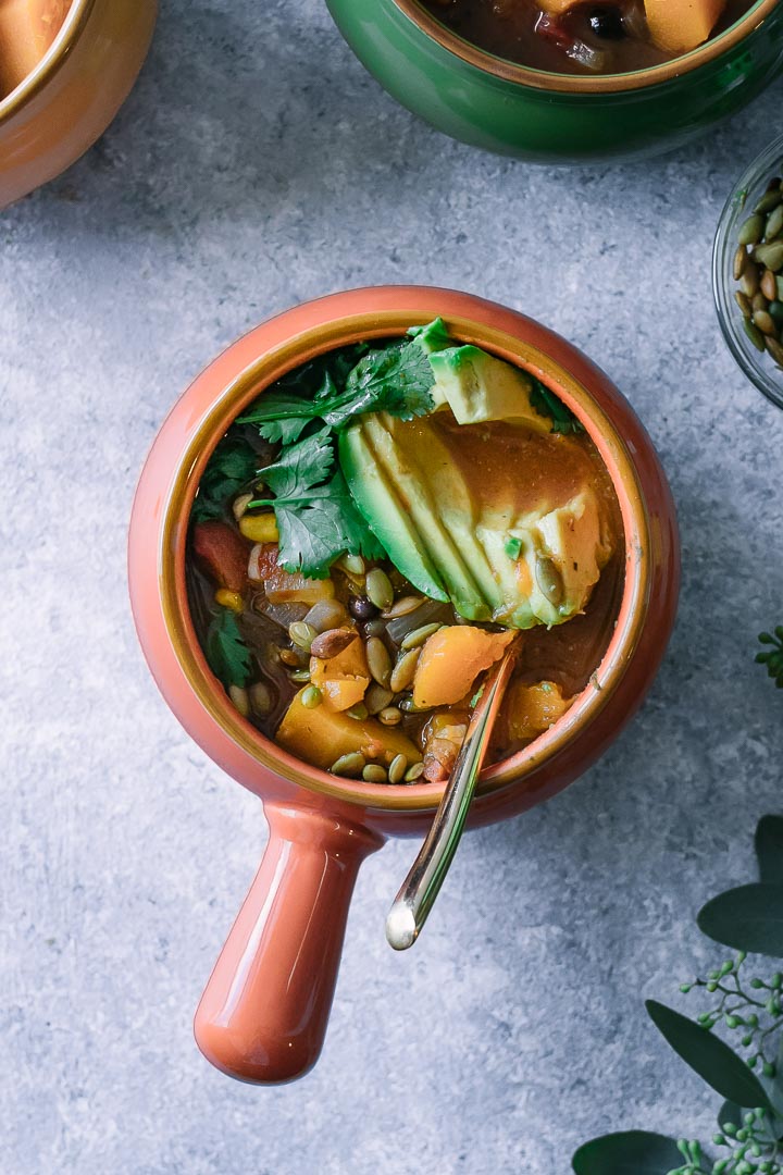 butternut squash chili in an orange soup bowl with a gold spoon