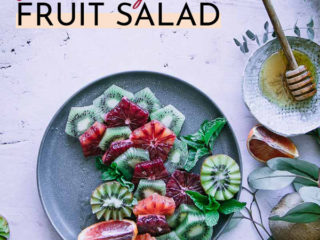 a fruit salad with oranges and kiwis on a blue plate and the words "blood orange kiwi fruit salad" in black and orange writing