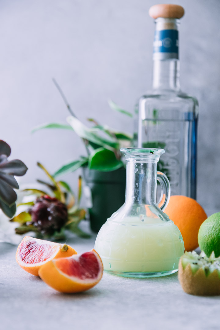 blood oranges, lime, and a small glass pitcher with lime juice on a white table