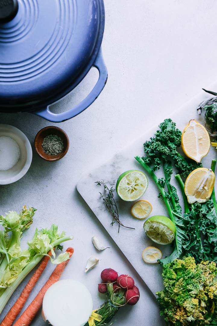 vegetable scraps on a white table with salt, pepper, and a soup pot for vegetable broth