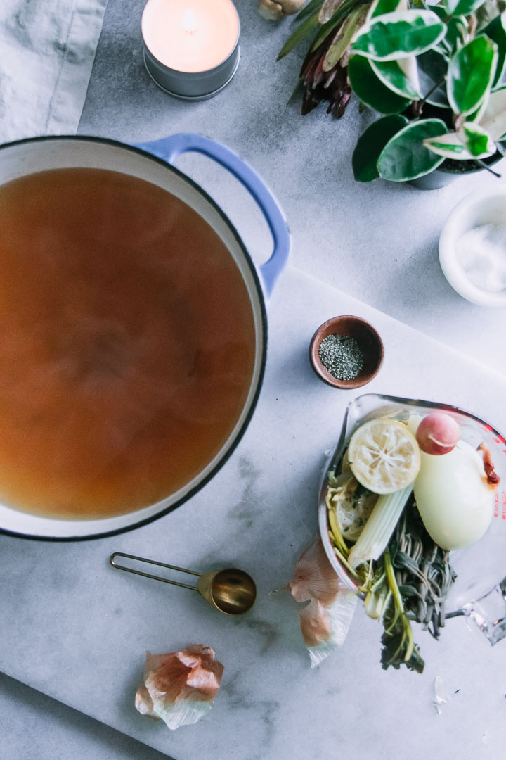 a blue ceramic dutch oven with vegetable broth and a glass bowl with leftover vegetable scraps