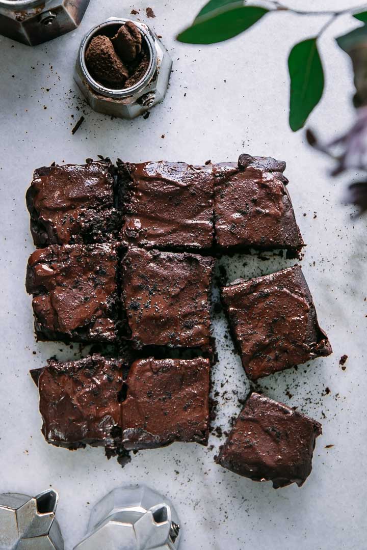 9 sliced brownies on a white marble table with an espresso maker with fresh espresso grounds