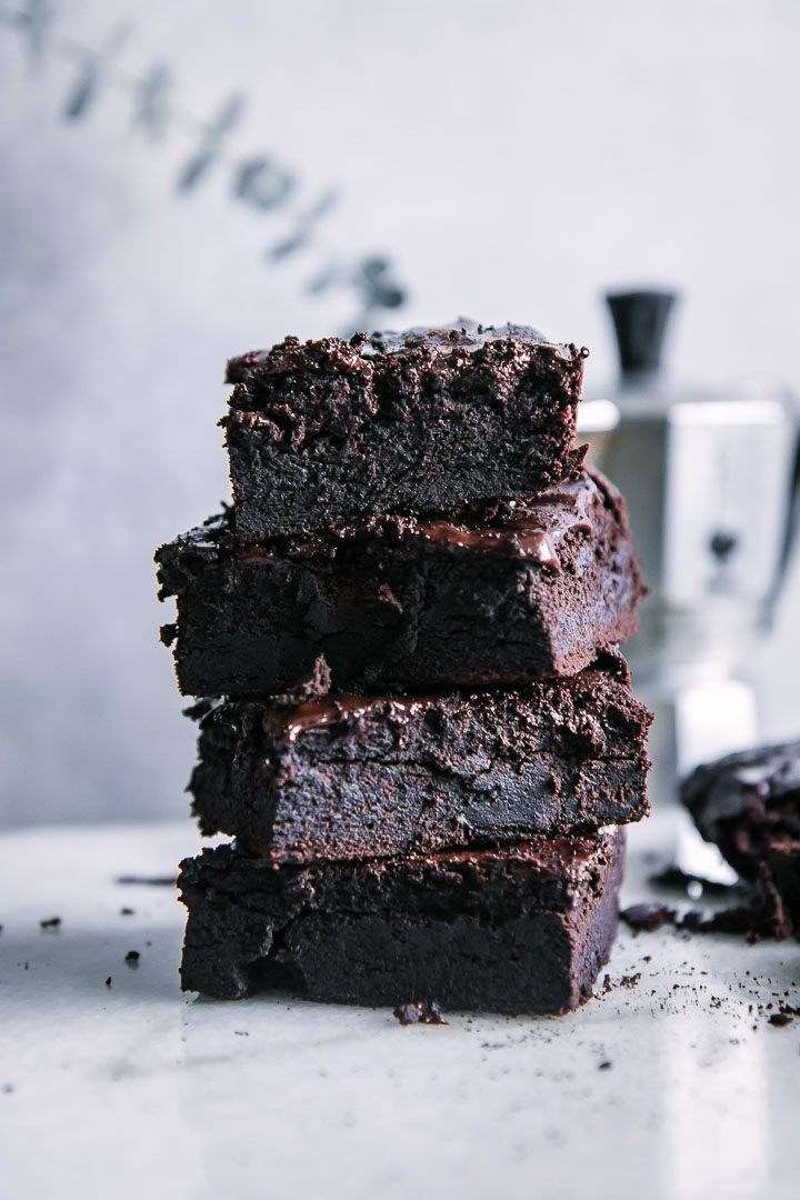 four stacked brownies on a white table with an espresso machine in the background