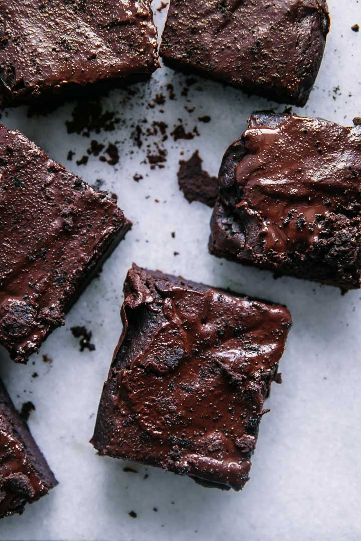 cut brownies with a chocolate drizzle and espresso grounds on a white table