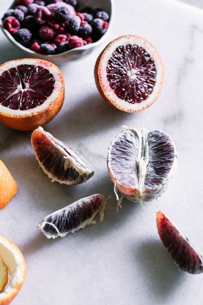 peeled blood oranges on a marble countertop