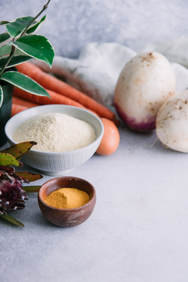 turnip carrot cakes on a plate with a ramekin of aioli on a white table