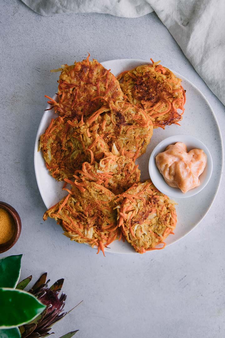 crispy carrot and turnips cakes on a white plate with orange garlic aioli