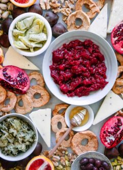 a platter with cranberry sauce, cheese, artichokes, sauerkraut, olives, and nuts