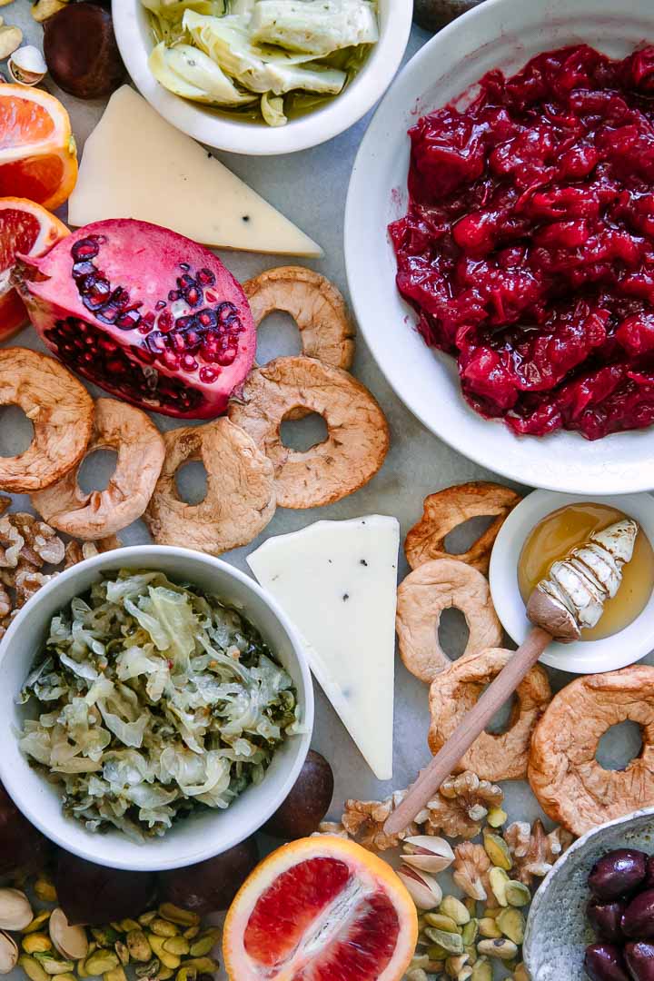 cheese, dried apple, sauerkraut, blood oranges, and nuts on a piece of marble