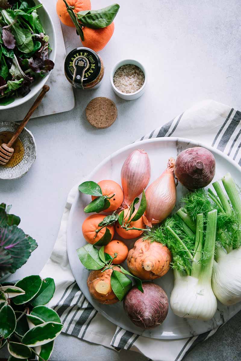 fennel, shallots, beets, oranges, honey, mixed greens, and salad on a white table