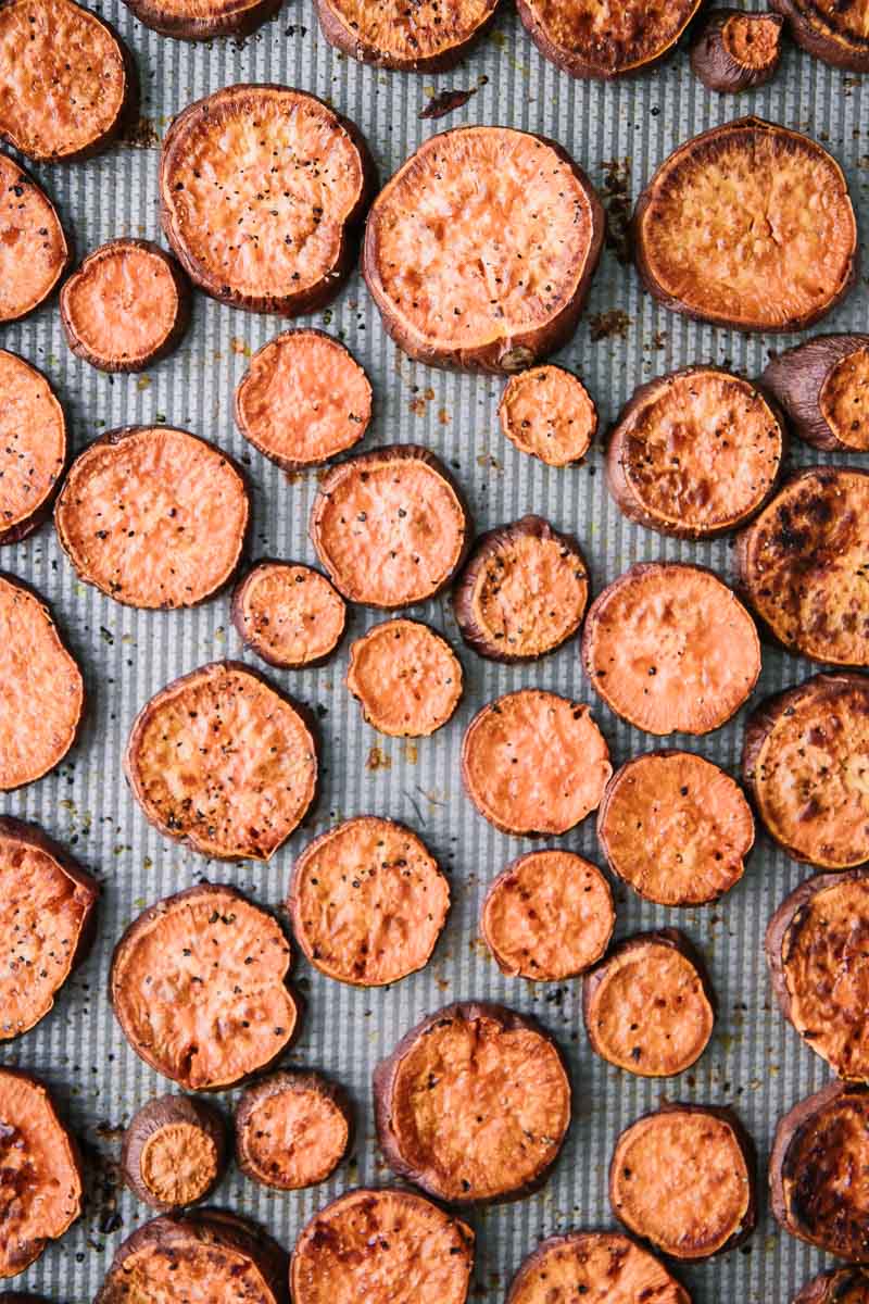 Sliced and roasted sweet potatoes on a silver sheetpan