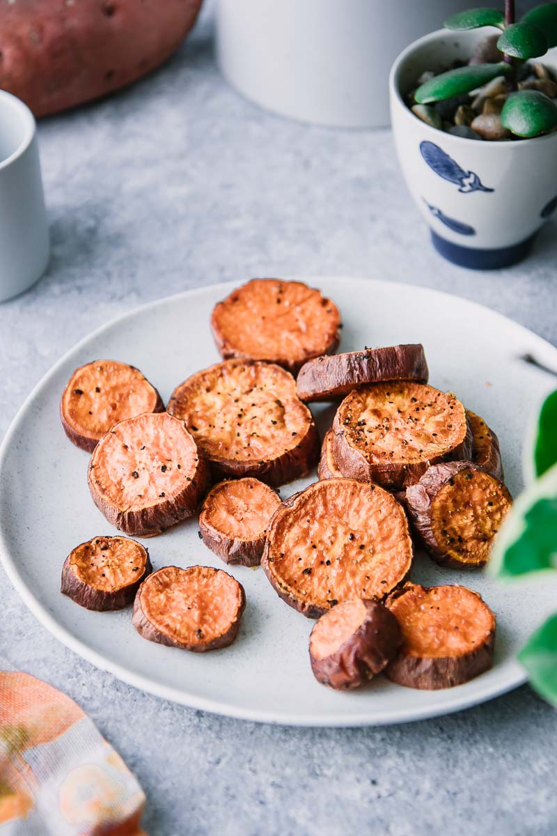 crispy vegan sweet potato wedges on a white plate on a blue table