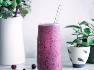 a purple smoothie on a white table with the words "triple berry banana smoothie" in black writing
