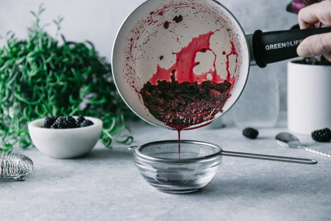 blackberry juice pouring from a pan through a mesh strainer