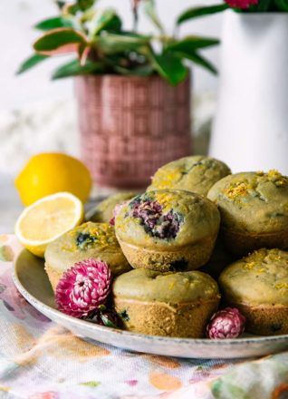 a plate with stacked lemon berry muffins and flowers on a white table