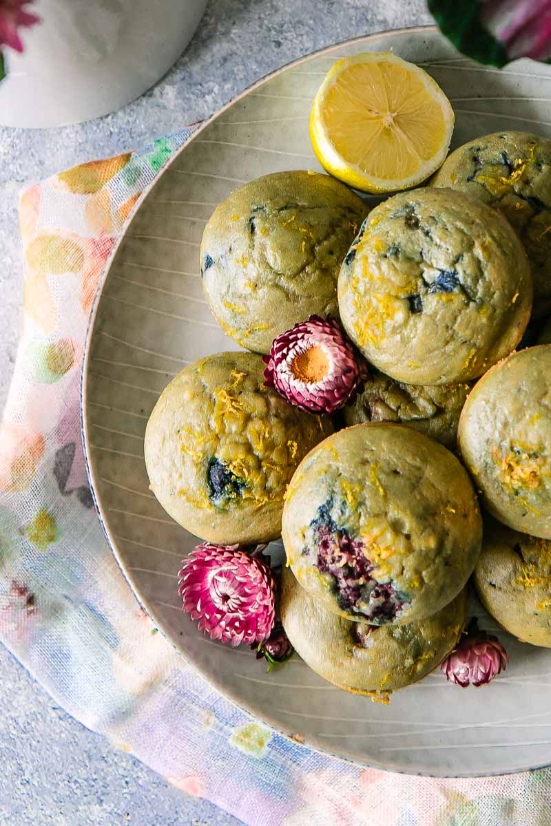 lemon berry muffins piled on a blue plate on a floral napkin